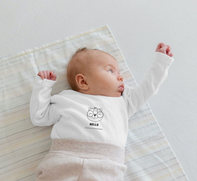 Little baby wearing a shirt with baby bear drawing on it