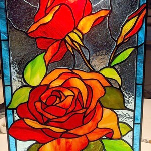May include: A stained glass window depicting two red roses with yellow and orange accents. The roses are set against a blue background with a black and white pattern.