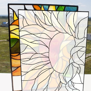 May include: A stained glass window depicting a sunflower with yellow, orange, and red petals. The sunflower is outlined in black and has a white center.