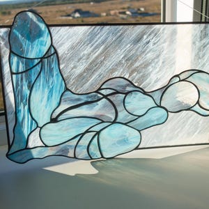 May include: A stained glass window depicting a stylized abstract figure in shades of blue and white.