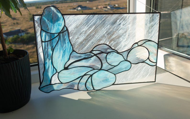 May include: A stained glass window depicting a stylized abstract figure in shades of blue and white.