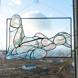 May include: A stained glass window depicting an abstract figure in shades of blue and brown. The figure is made up of many small pieces of glass, creating a textured and organic look.