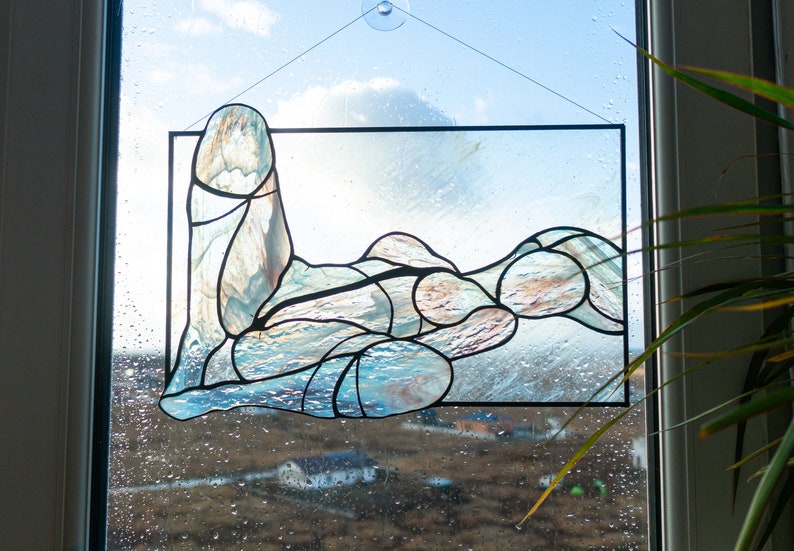 May include: A stained glass window depicting an abstract figure in shades of blue and brown. The figure is made up of many small pieces of glass, creating a textured and organic look.