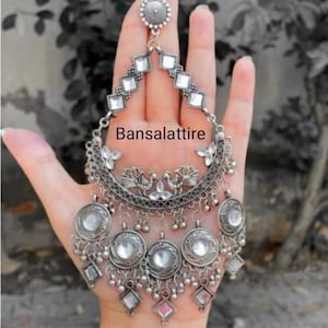 May include: Silver tone dangle earrings with multiple tiers of round and square mirrored accents. The earrings feature a crescent moon design with a floral pattern and two birds. The text "Bansalattire" is visible in the image.