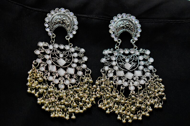 May include: A pair of silver dangle earrings with white stones and a beaded fringe.