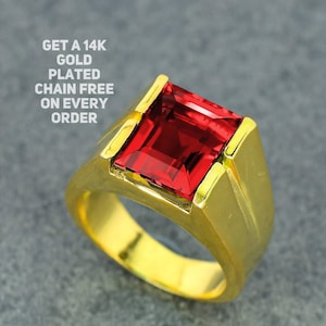May include: A gold-plated ring with a large, square-cut, red gemstone. The ring has a thick band and a bezel setting. Text on the image reads: GET A 14K GOLD PLATED CHAIN FREE ON EVERY ORDER.