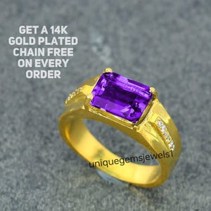 May include: A gold-plated ring with a large, rectangular, purple gemstone. The ring has small, clear stones on the sides and the text "uniquegemsjewels1". The image also includes the text "GET A 14K GOLD PLATED CHAIN FREE ON EVERY ORDER".