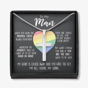 Pu&ograve; includere: Una collana d'argento con un ciondolo a forma di croce in una scatola nera. La scatola presenta un cuore arcobaleno con il testo "To My Man" e un messaggio su una croce di promessa e un viaggio fatto mano nella mano.