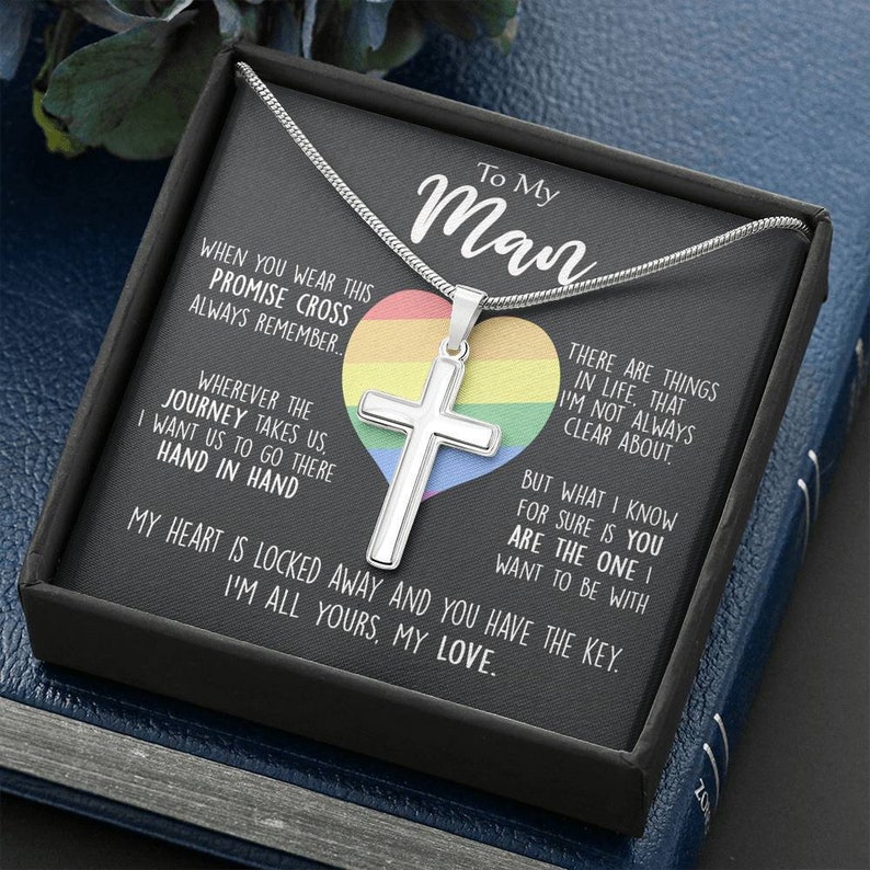 Pu&ograve; includere: Una collana d'argento con un ciondolo a forma di croce e un ciondolo a forma di cuore arcobaleno in una scatola nera. La scatola contiene un messaggio che dice "To My Man" e include un messaggio sincero sull'amore e l'impegno.