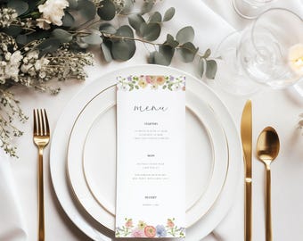Op de afbeelding: Een bloemig huwelijksmenu met een witte achtergrond en een rand van aquarelbloemen. Het menu vermeldt "Voorgerechten", "Hoofdgerecht" en "Dessert".