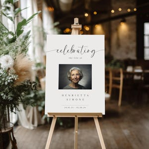 May include: White sign with black text that reads "celebrating the life of Henrietta Simone 24.05.55 - 02.06.24". A black and white photo of a woman is in the center of the sign.