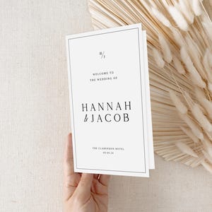 May include: White wedding order of service with black text. The order of service says "Welcome to the wedding of Hannah & Jacob" and "The Clarendon Hotel 05.05.14".