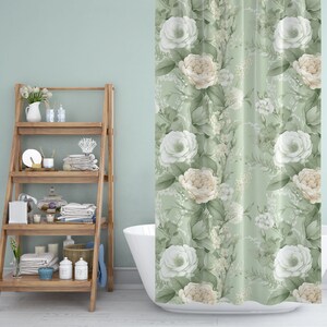 K&ouml;nnte beinhalten: Eine wei&szlig;e Badewanne mit einem gr&uuml;nen floralen Duschvorhang mit wei&szlig;en und cremefarbenen Rosen. Im Hintergrund befindet sich ein Holzregal mit verschiedenen Badezimmerartikeln.