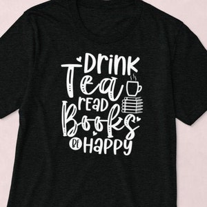 Può includere: Maglietta nera con testo bianco che dice "Drink Tea Read Books Be Happy" con una grafica di una tazza di tè e libri impilati.