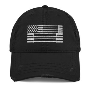 May include: Black distressed baseball cap featuring a white embroidered design of the American flag. The flag design is stylized with barbell shapes and stars. The cap has a curved brim and a worn, vintage look.