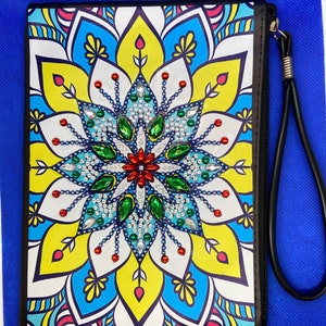 May include: A black zippered pouch with a colorful mandala design featuring a central flower with green, blue, and red rhinestones. The pouch has a black strap.