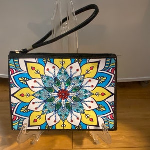 May include: A black zippered clutch with a colorful mandala design featuring a large blue, green, and red rhinestone flower in the center. The clutch has a black strap.