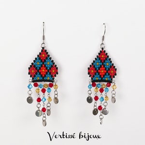 Op de afbeelding: Een paar kralen oorbellen met een geometrisch ontwerp in rood, blauw en geel. De oorbellen hebben een driehoekige vorm met bungelende kralen en kleine zilveren schijfjes. De tekst "Vertissé bijoux" staat onderaan.