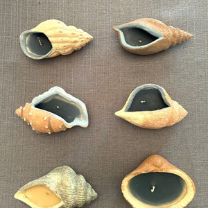 May include: A set of three ceramic mugs with a speckled, matte finish. The mugs are in shades of cream, light gray, and dark gray. Each mug has a simple, modern design and a rounded handle. The mugs are stacked on top of each other.