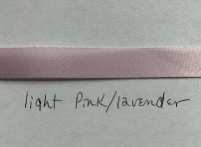 May include: A horizontal strip of smooth, light pink or lavender satin ribbon. Below the ribbon, the handwritten text reads light Pink/lavender in black ink. The ribbon has a subtle sheen and a consistent width across the entire frame.