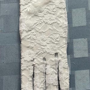 May include: White lace gloves with a delicate floral pattern and a ruffled edge.