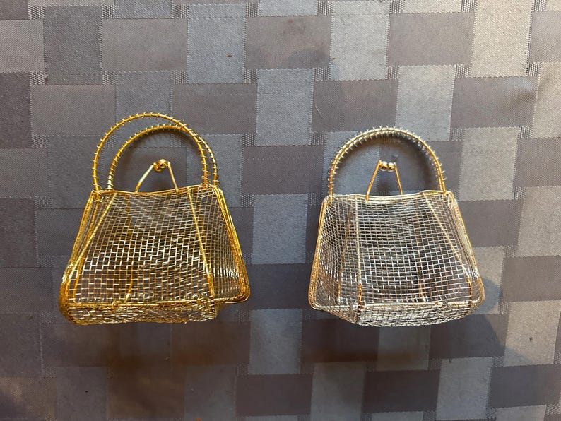 May include: Two wire mesh handbags, one gold and one silver, with a handle on top.