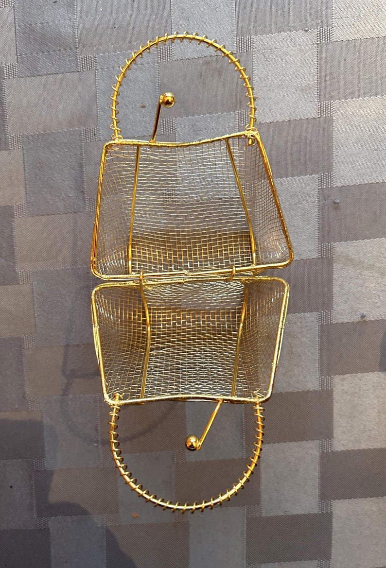 May include: A gold wire mesh basket with two sections and a handle. The basket is open and the wire mesh is visible.