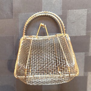May include: A gold wire mesh handbag with a wire handle.