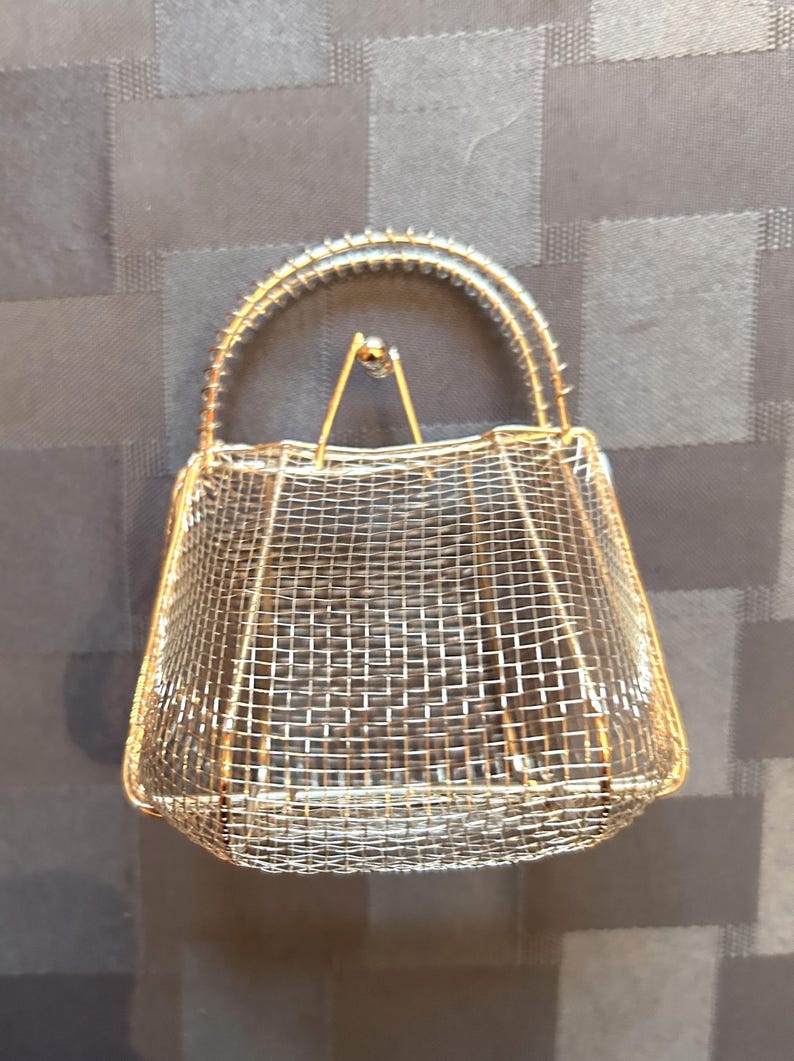 May include: A gold wire mesh handbag with a wire handle.