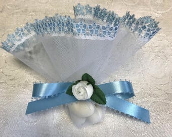 May include: A white tulle favor bag featuring a light blue lace trim along the top edge. The bag is cinched with a light blue satin ribbon tied in a bow, accented by a small white artificial rose with two green fabric leaves attached to the center.
