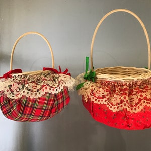 May include: Two red and white plaid baskets with lace trim and wooden handles. The larger basket has a green bow and the smaller basket has a red bow.
