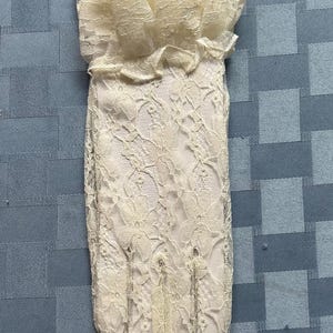 May include: A pair of white lace gloves with a ruffled cuff. The gloves are made of delicate lace and have a classic design.