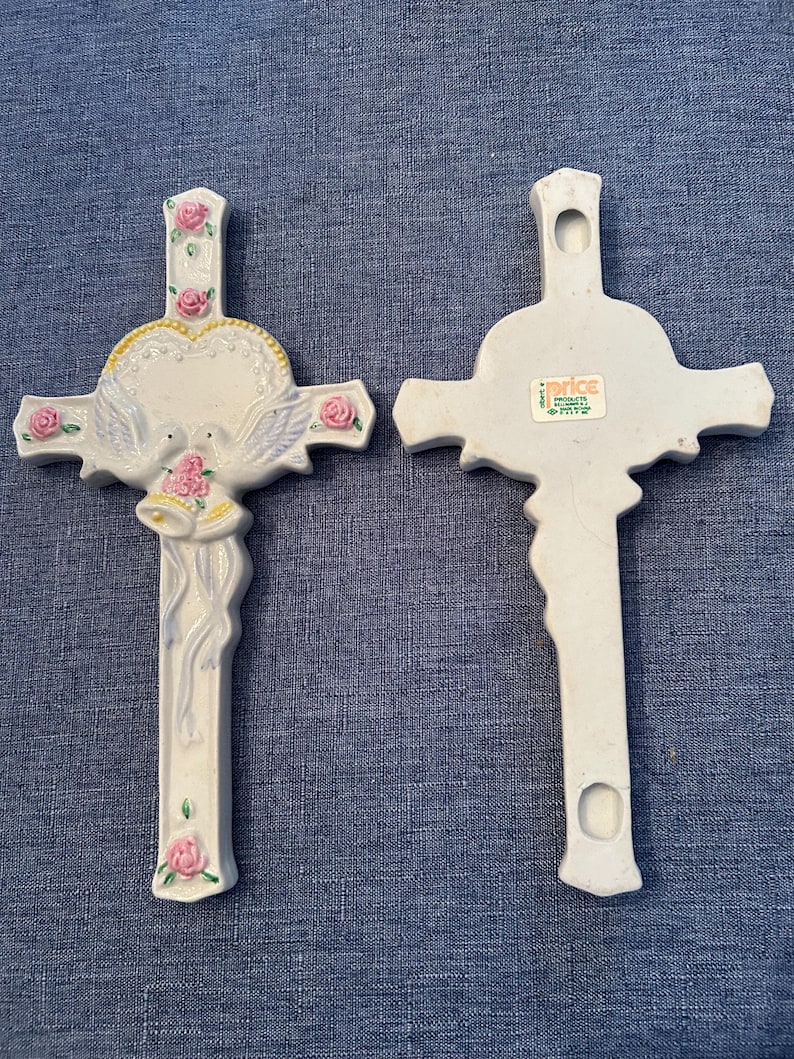 May include: White ceramic cross with a heart, doves, and wedding bells. The back of the cross has a "Price" sticker with the text "Products of the World, Inc.  Made in Taiwan".
