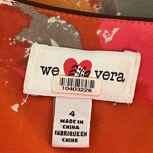 K&ouml;nnte beinhalten: Ein wei&szlig;es Etikett mit dem Text "we love vera" und einem roten Herzen mit einem schwarz-wei&szlig;en Design. Das Etikett hat auch einen Barcode mit der Nummer 10403226. Unter dem Etikett befindet sich ein kleineres wei&szlig;es Etikett mit dem Text "4", "Made in China" und "Fabrique en Chine".