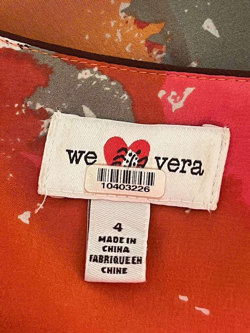 K&ouml;nnte beinhalten: Ein wei&szlig;es Etikett mit dem Text "we love vera" und einem roten Herzen mit einem schwarz-wei&szlig;en Design. Das Etikett hat auch einen Barcode mit der Nummer 10403226. Unter dem Etikett befindet sich ein kleineres wei&szlig;es Etikett mit dem Text "4", "Made in China" und "Fabrique en Chine".
