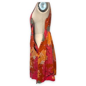 K&ouml;nnte beinhalten: Ein &auml;rmelloses Kleid mit einem abstrakten Druck in Rosa, Orange und Grau. Das Kleid hat einen figurbetonten Oberteil und einen flie&szlig;enden Rock.