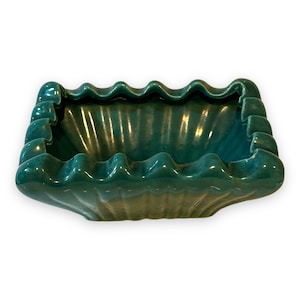 以下が含まれることがあります： 波打つような波状の内部と、波状の縁を持つ、ターコイズグリーンのセラミック製の灰皿です。