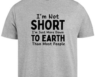 Puede incluir: Camiseta gris jaspeado con texto negro: "I'm Not SHORT I'm Just More Down TO EARTH Than Most People". La camiseta tiene mangas cortas y cuello redondo.