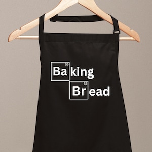 Könnte beinhalten: Schwarze Schürze mit weißem Text, der "Baking Bread" in einer Schriftart im Stil des Periodensystems lautet.