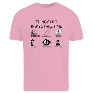 Puede incluir: Una camiseta de manga corta de color rosa claro con texto negro que dice THINGS I DO IN MY SPARE TIME, acompa&ntilde;ada de seis peque&ntilde;os iconos gr&aacute;ficos negros que representan actividades de pesca con etiquetas como GO FISHING y DREAM ABOUT FISHING.