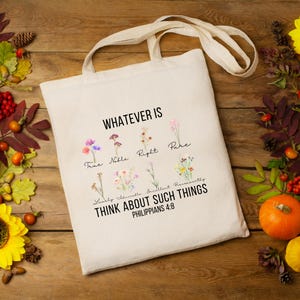 May include: A white tote bag with a floral design and the text "Whatever is True, Noble, Right, Pure, Lovely, Admirable, Excellent, Respectable, Think About Such Things Philippians 4:8".