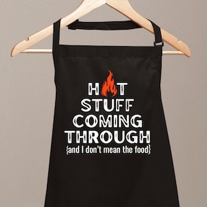 May include: Black apron with white text that reads "HOT STUFF COMING THROUGH {and I don't mean the food}". A red flame graphic is above the text.