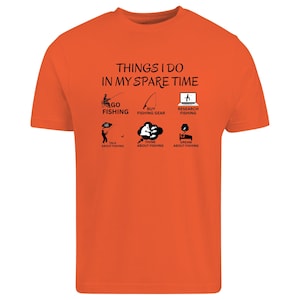 Puede incluir: Una camiseta de manga corta de color naranja brillante con el texto negro THINGS I DO IN MY SPARE TIME. Debajo del texto hay seis iconos gr&aacute;ficos negros que representan actividades de pesca, como ir a pescar, comprar equipo y buscar informaci&oacute;n.