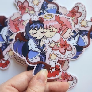 May include: A collection of anime-style stickers featuring two characters embracing. One character has dark blue hair, devil wings, and a tail, while the other has pink hair and a halo. The stickers are on a white background.