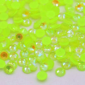May include: A large assortment of neon yellow rhinestones in various sizes and shapes. The rhinestones have a clear, iridescent finish.
