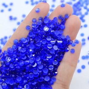Puede incluir: Un montón grande de pequeños diamantes de imitación redondos de color azul real.