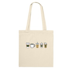Puede incluir: Una bolsa de tela beige con un gráfico de cinco bebidas de café diferentes, que incluyen una taza de café, un latte y tres cafés helados. Las bebidas están todas en fila y tienen el logotipo de Starbucks.