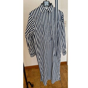 May include: A long-sleeved, striped shirt dress with a button-up front and a tie at the neck. The dress is black and white with vertical stripes.
