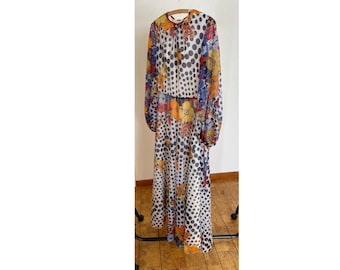 May include: A long-sleeved maxi dress with a white background and a black polka dot pattern. The dress has a floral print overlay in shades of orange, yellow, blue, and red.