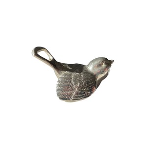 Può includere: Un apribottiglie d'argento a forma di uccello con un design dettagliato. L'apribottiglie ha un anello in cima per appenderlo.